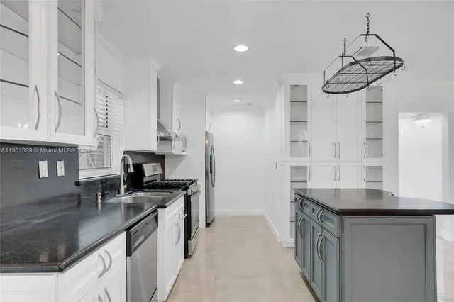 a kitchen with stainless steel appliances a sink a stove a refrigerator and cabinets