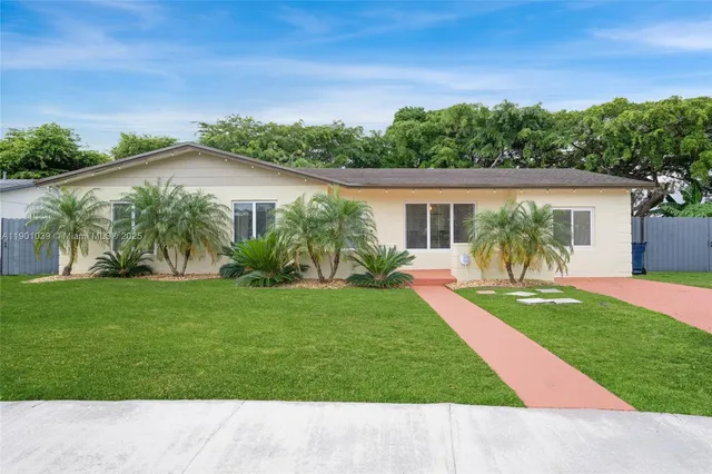 a front view of a house with a yard and palm trees