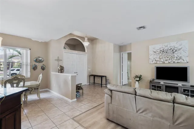 a very nice looking dining room with kitchen island furniture a chandelier a large window and kitchen view