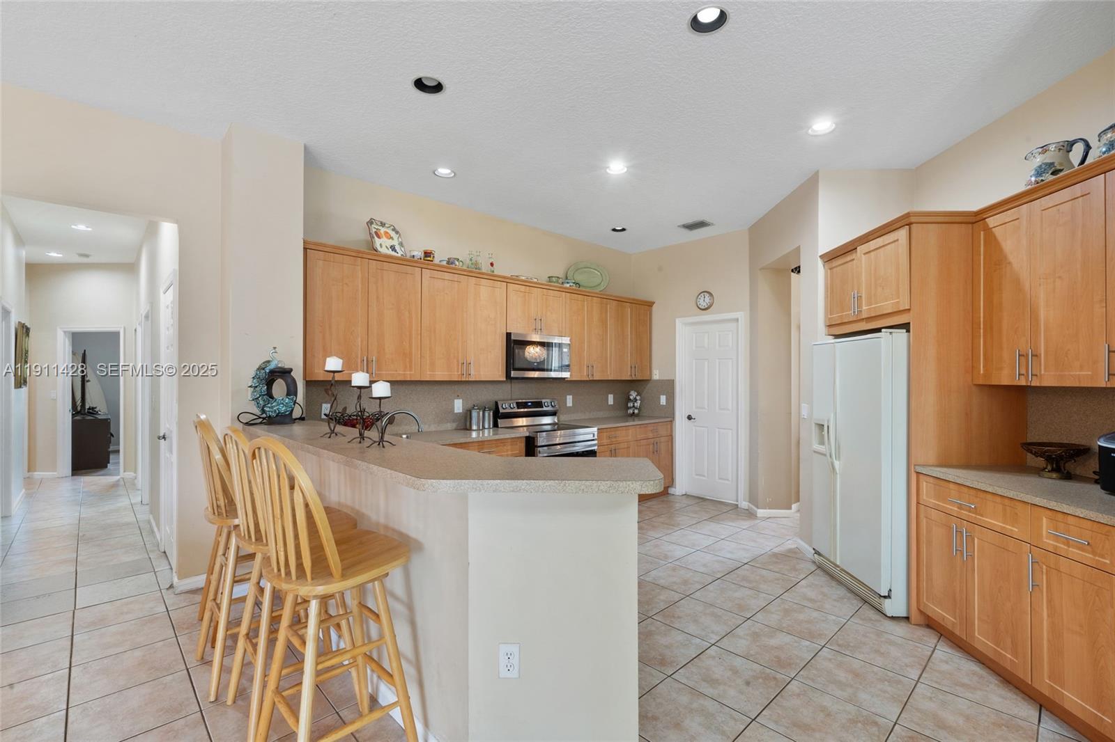 13875 Southwest 41st Street Davie, FL 33330 - Photo 19 of 62 a kitchen with stainless steel appliances kitchen island granite countertop a refrigerator and a sink
