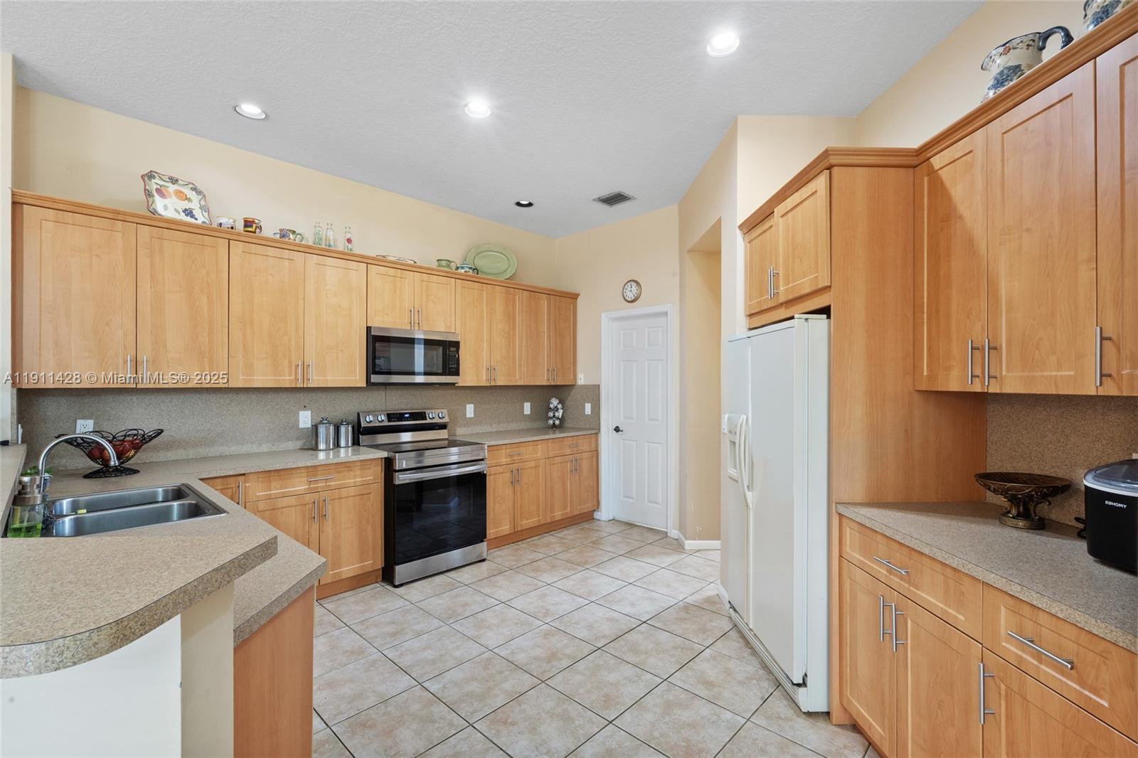 13875 Southwest 41st Street Davie, FL 33330 - Photo 20 of 62 a kitchen with stainless steel appliances granite countertop a refrigerator sink and cabinets