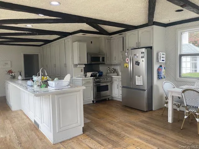 a kitchen with stainless steel appliances kitchen island granite countertop a refrigerator a stove a sink dishwasher and a dining table with wooden floor