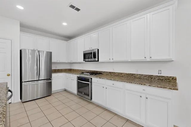 a kitchen with granite countertop white cabinets and stainless steel appliances
