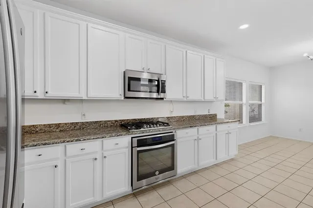 a kitchen with granite countertop white cabinets and stainless steel appliances