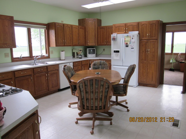 18444 University Road Malta, IL 60150 - Photo 3 of 25 a kitchen with a refrigerator a stove a sink dishwasher with a dining table and chair