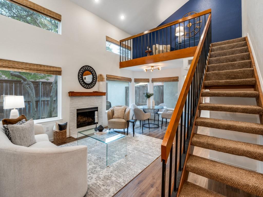 18040 Midway Road, Unit 189 Dallas, TX 75287 - Photo 2 of 28 Living room with a fireplace with flush hearth, plenty of natural light, wood finished floors, stairway, and high vaulted ceiling