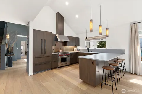 a kitchen with stainless steel appliances kitchen island granite countertop a refrigerator a oven a sink a stove and a center island with wooden floor