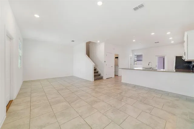 an empty room with white walls and kitchen view