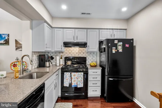 a kitchen with stainless steel appliances granite countertop a refrigerator a stove a sink dishwasher and a refrigerator with wooden cabinets