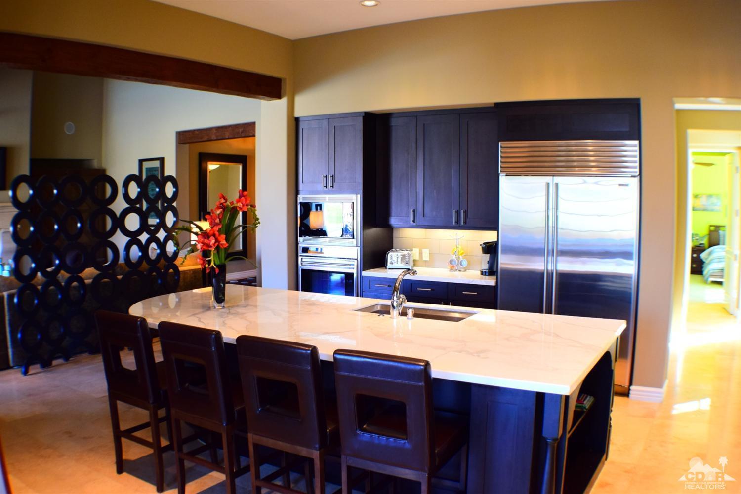 9 Santa Rosa Mountain Lane Rancho Mirage, CA 92270 - Photo 21 of 58 a kitchen with stainless steel appliances kitchen island granite countertop a table chairs and a refrigerator