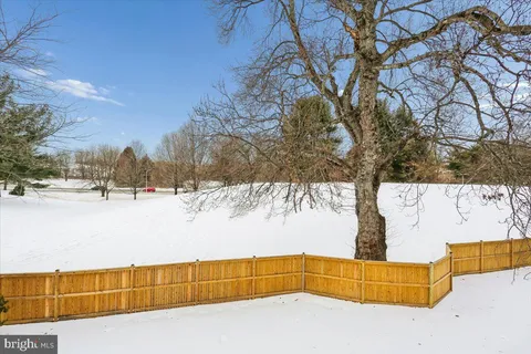 a backyard of a house with a large tree and wooden fence