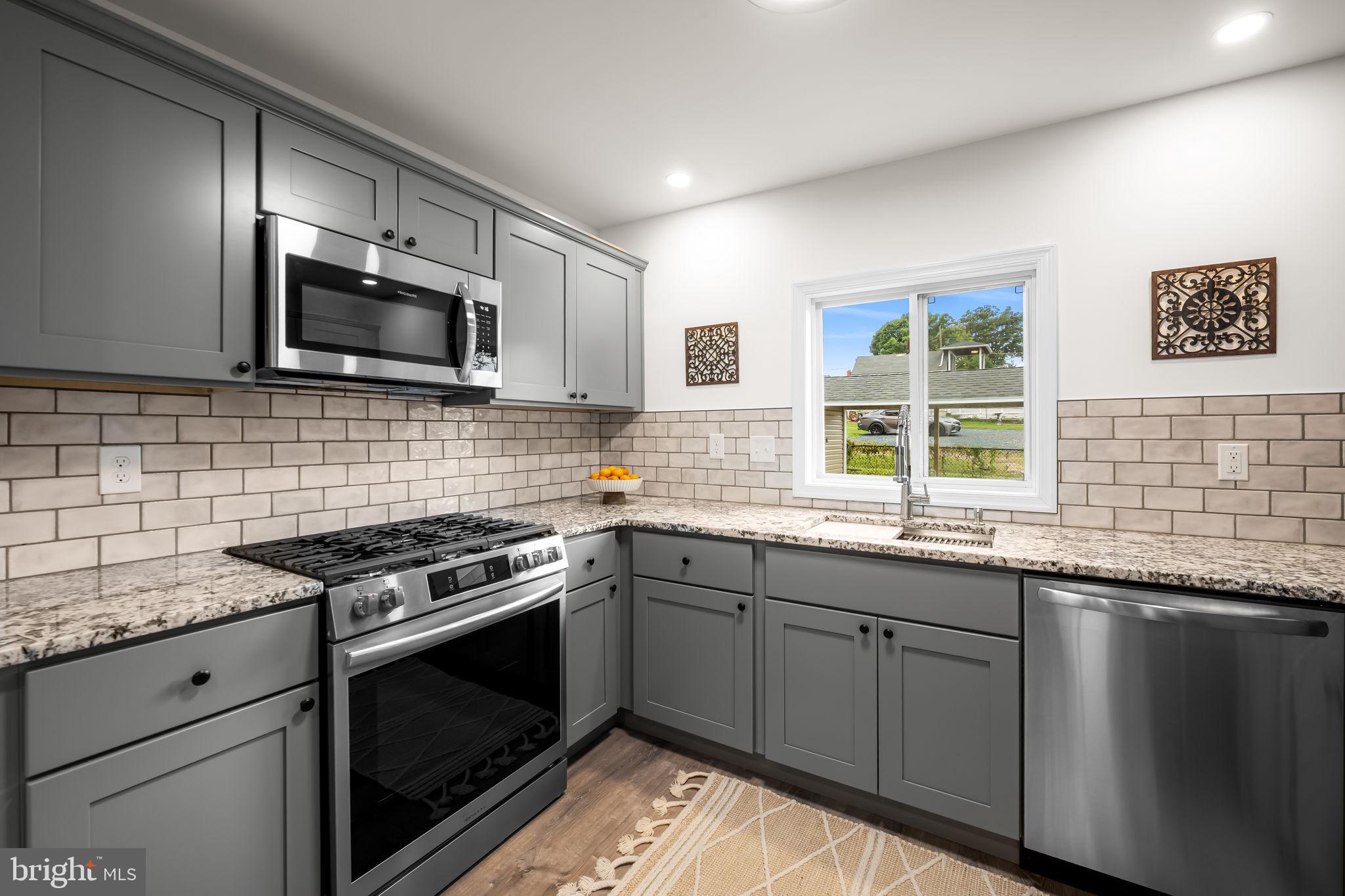 628 North Stuart Street Baltimore, MD 21221 - Photo 12 of 39 a kitchen with stainless steel appliances granite countertop a sink stove microwave and cabinets