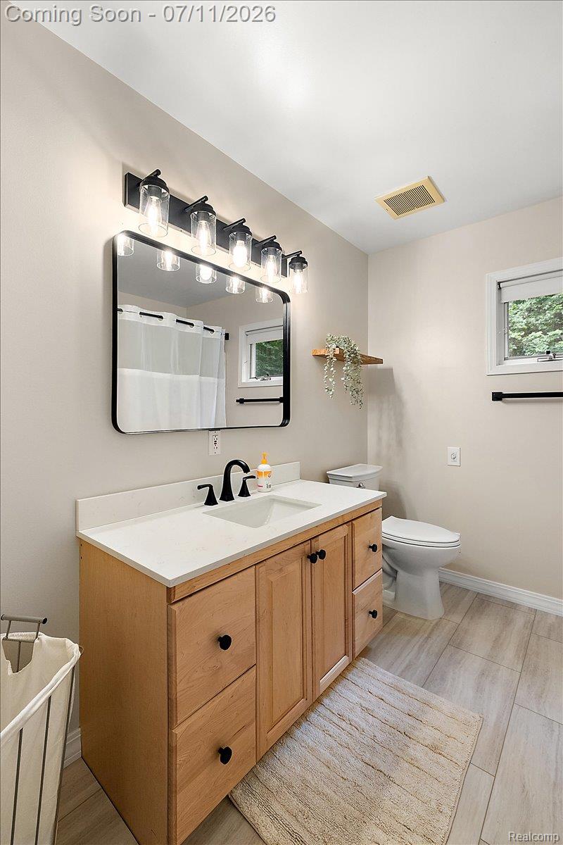 4219 Gardner Road Metamora, MI 48455 - Photo 39 of 87 Bathroom featuring a wood-finish vanity with a white countertop and integrated sink, matte black faucet, and a rectangular mirror with black trim