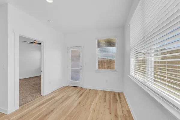 a view of an empty room with wooden floor and a window