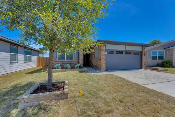 a view of a house with backyard and a tree