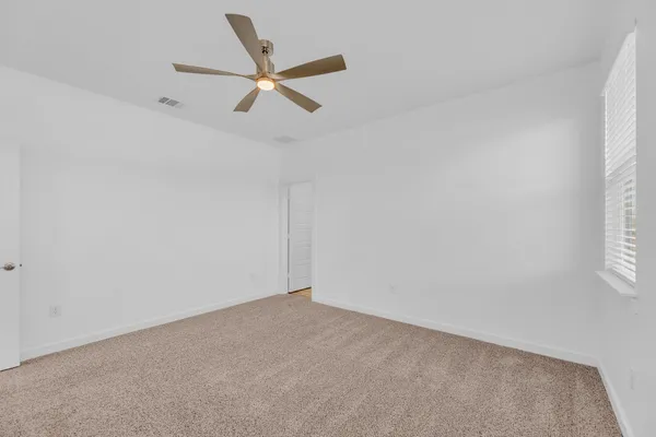an empty room with windows and fan