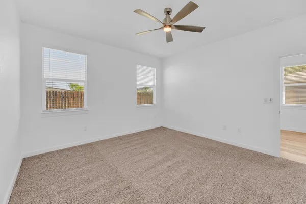 an empty room with a ceiling fan and a window