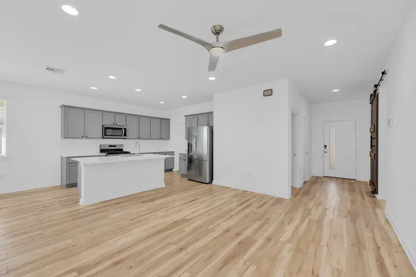 a view of a kitchen with kitchen island a sink wooden floor and a refrigerator