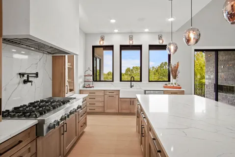a large kitchen with stainless steel appliances a large counter top a stove and a sink