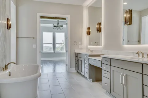 a bathroom with double vanity sink a two mirror a window and a bathtub