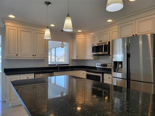 a kitchen with granite countertop a stove a sink and a refrigerator