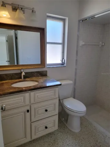 a bathroom with a granite countertop toilet sink and mirror