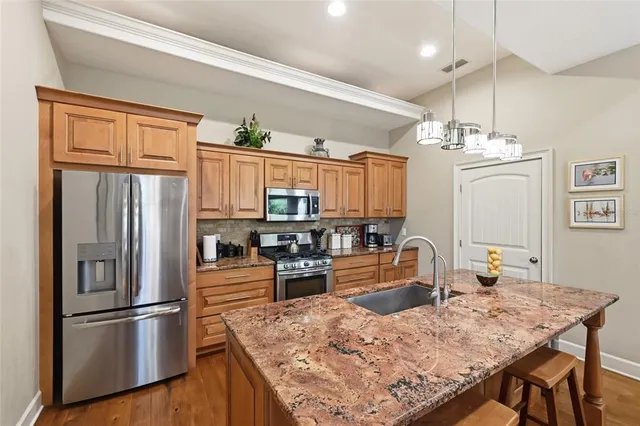 a kitchen with granite countertop a refrigerator stove top oven and sink