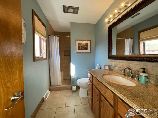 a bathroom with a granite countertop sink a toilet and a mirror