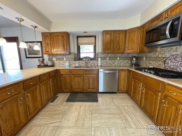 a kitchen with stainless steel appliances kitchen island granite countertop a sink a stove top oven a counter space and cabinets