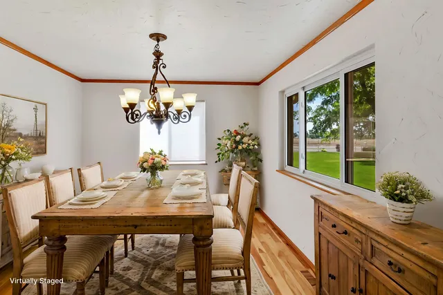 a view of a dining room with furniture a chandelier and large windows