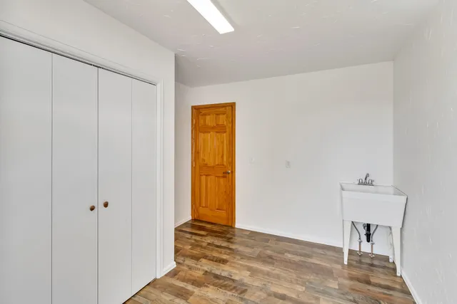 a view of empty room with wooden floor and bathroom