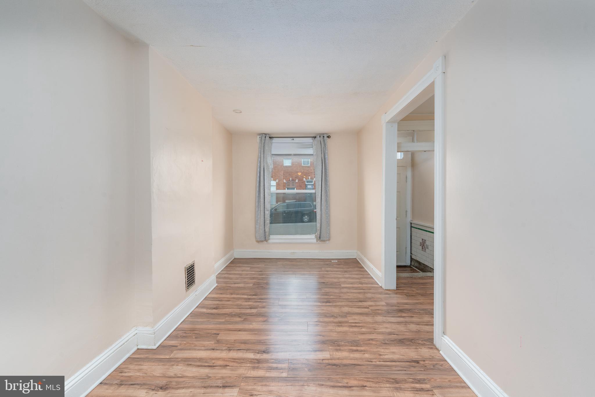 514 Brunswick Street Baltimore, MD 21223 - Photo 5 of 26 a view of an empty room with wooden floor and a window