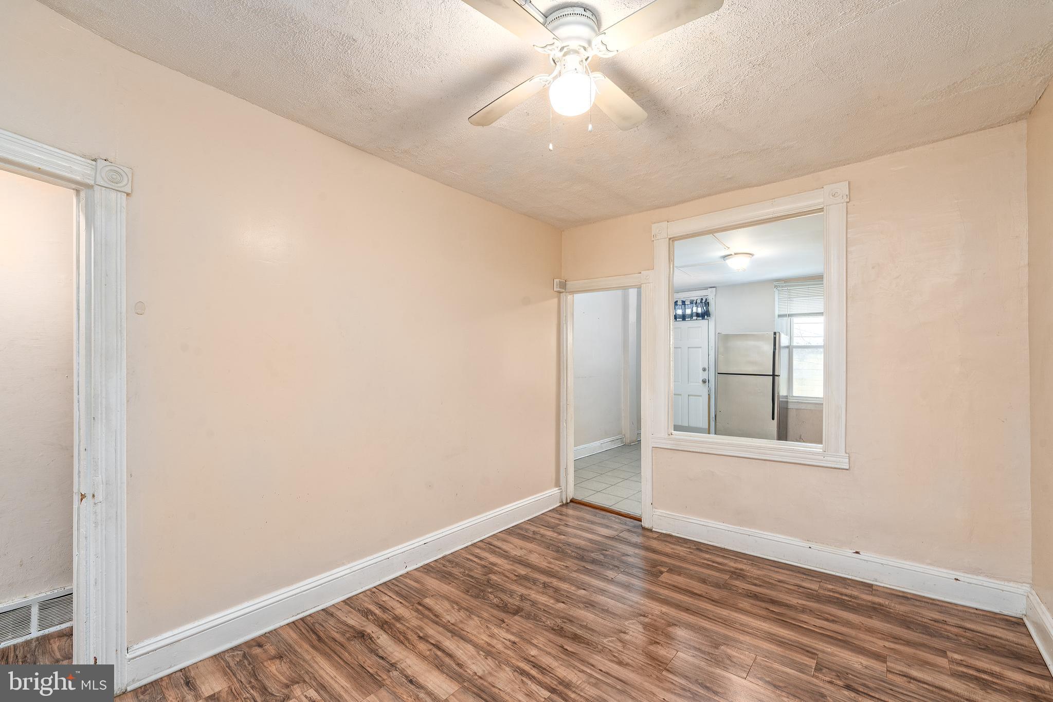 514 Brunswick Street Baltimore, MD 21223 - Photo 7 of 26 an empty room with wooden floor fan and windows