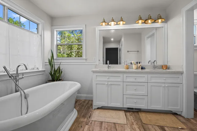 a bathroom with a tub a sink and a window