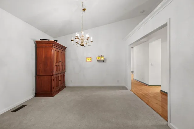 a view of an empty room with chandelier fan