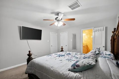 a bedroom with a bed and a flat tv screen on dresser