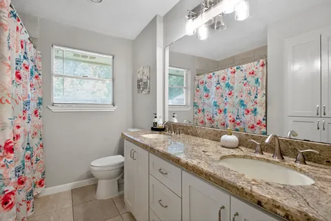 a bathroom with a granite countertop sink a mirror and a toilet