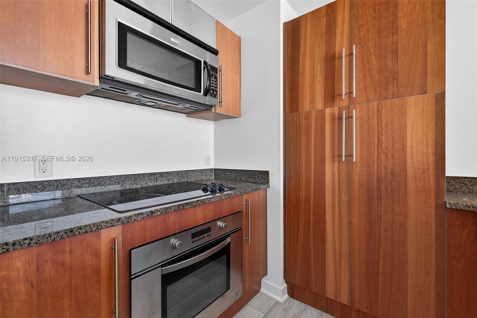 300 South Biscayne Boulevard, Unit T2407 Miami, FL 33131 - Photo 13 of 39 a kitchen with granite countertop white cabinets and stainless steel appliances