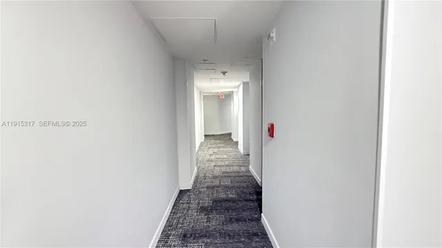 a view of a hallway with wooden floor and a bathroom