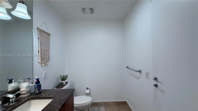 a bathroom with a granite countertop toilet and sink