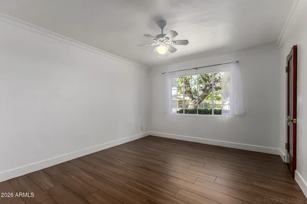 a view of an empty room with wooden floor and a window