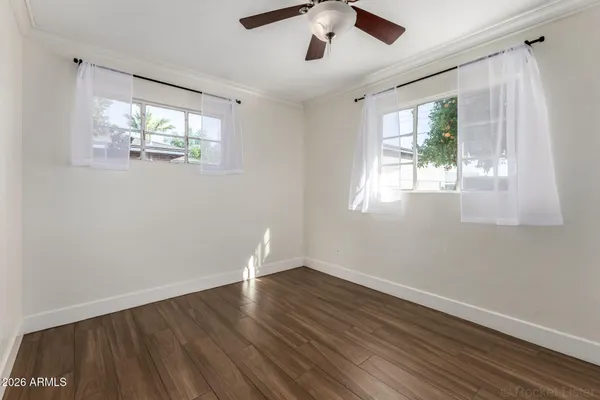 an empty room with wooden floor and windows