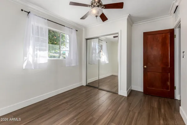 an empty room with wooden floor a ceiling fan and windows