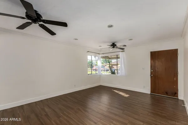 a view of an empty room with wooden floor and a window
