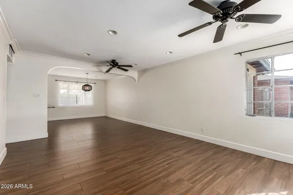 an empty room with wooden floor chandelier and windows