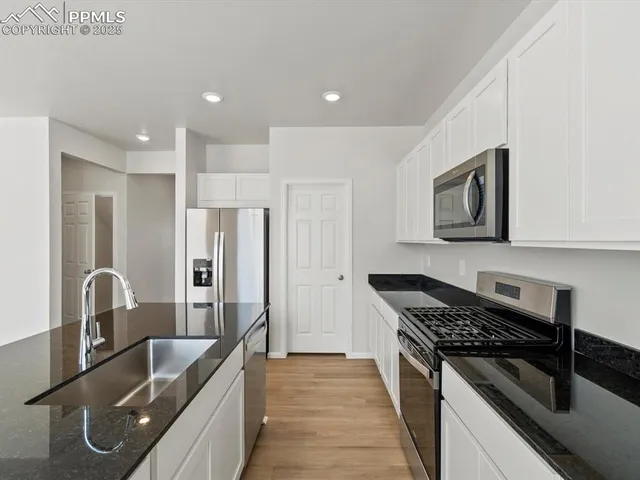 a kitchen with granite countertop a sink stainless steel appliances and cabinets