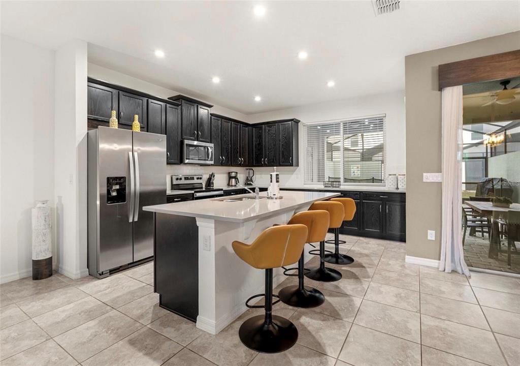 2163 Copper Bell Place Kissimmee, FL 34747 - Photo 16 of 41 a kitchen with stainless steel appliances granite countertop a refrigerator and a stove top oven