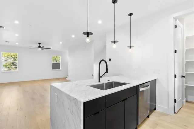 a kitchen with a sink dishwasher and a wooden floor