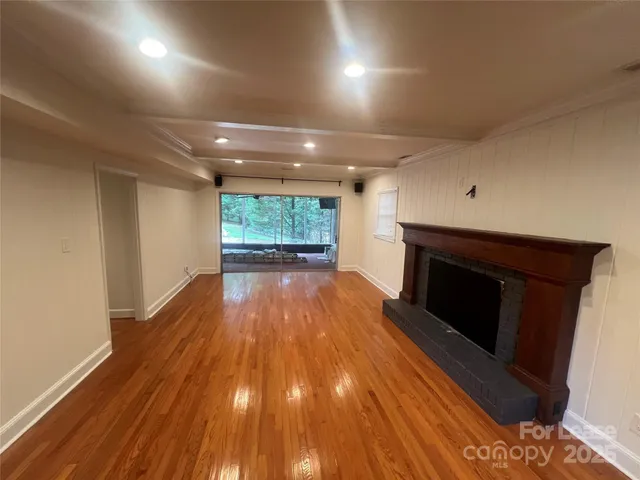a view of an empty room with wooden floor fire place