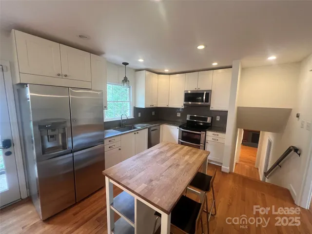 a kitchen with granite countertop stainless steel appliances a refrigerator and a stove top oven